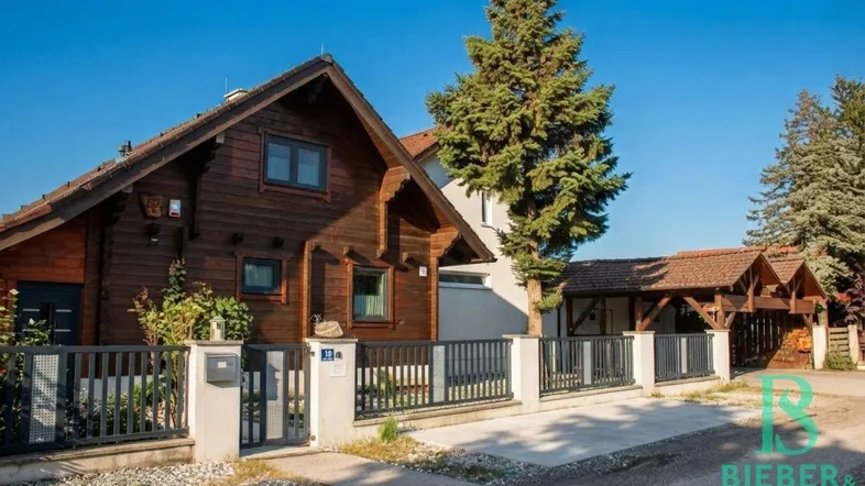 Charmantes Holzhaus mit gepflegtem Vorgarten und Zaun unter blauem Himmel.