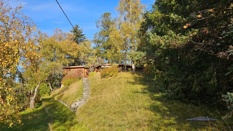 Das Anwesen liegt auf einem grünen Hügel, umgeben von Bäumen und natürlicher Landschaft.