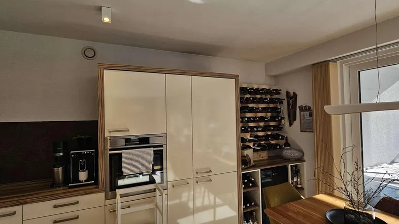 Moderne Küche mit integrierten Geräten, Weinschrank und Holzakzenten für eine stilvolle Einrichtung.