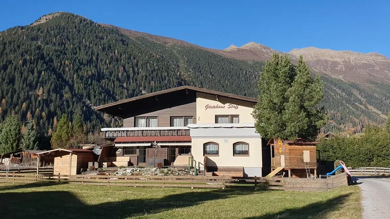 Traditionelles Gasthaus in alpiner Umgebung mit Spielplatz und Bergblick.