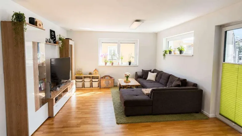 Helles Wohnzimmer mit Holzboden, großem Ecksofa und Medienwand mit Stauraum.