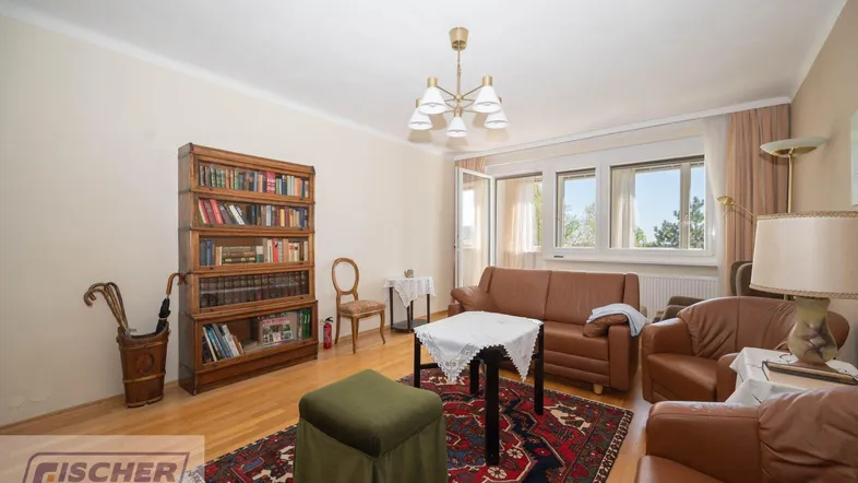 Gemütliches Wohnzimmer mit Holzboden, Ledersofas und einem Bücherregal, mit Zugang zum Balkon.