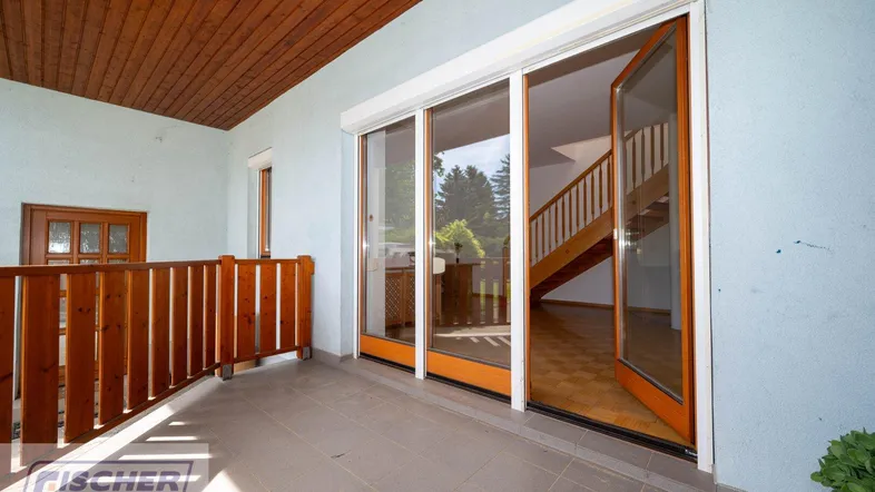 Geräumiger Balkon mit Holzgeländer und Zugang zum Innenbereich.