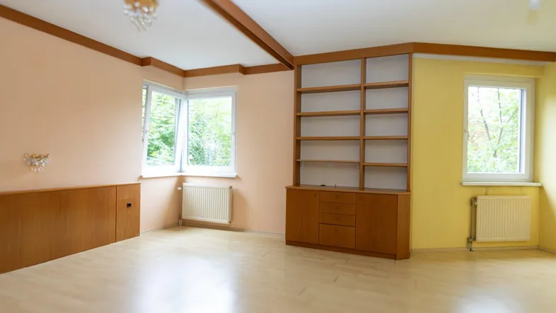 Helles Zimmer mit Einbauregal, Holzdeckenbalken und Laminatboden, ideal als Wohn- oder Schlafzimmer.