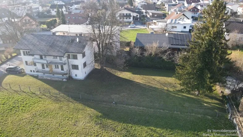 Luftaufnahme eines Hauses mit großem Grundstück und umliegender Wohnbebauung in sonniger Lage.