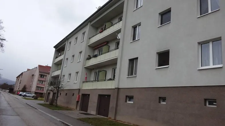 Mehrstöckiges Wohngebäude mit Balkonen und Garagenzufahrten an einer Straße.