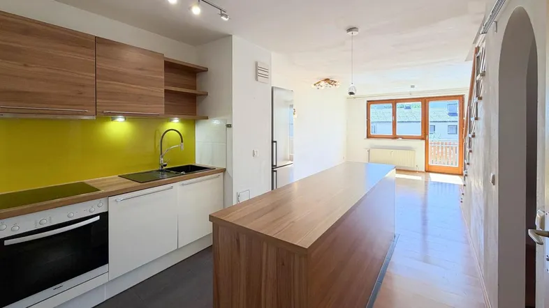 Moderne offene Küche mit Holzelementen, gelber Rückwand und integrierter Kochinsel.