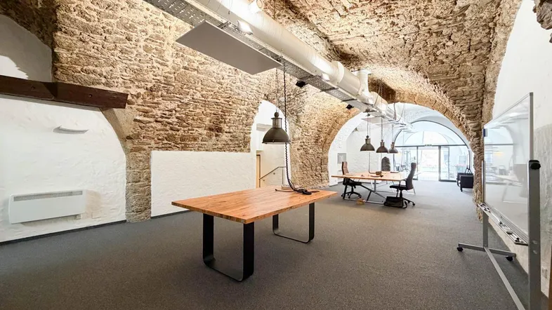 Geräumiges Büro in einem historischen Gewölbekeller mit freigelegten Steinwänden und modernen Arbeitsplätzen.