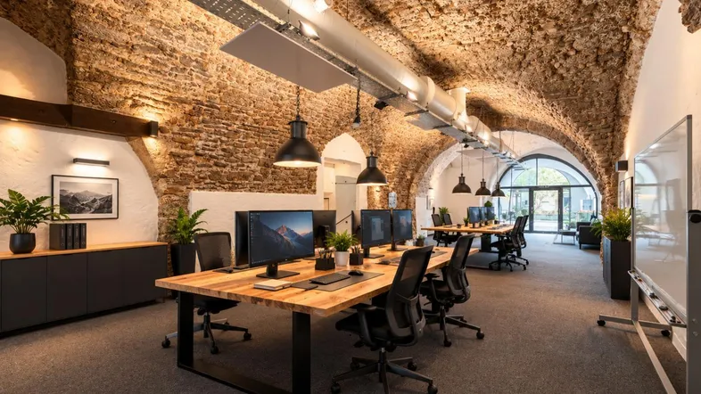 Geräumiges Büro mit freiliegenden Ziegelgewölbedecken, modernen Arbeitsplätzen und viel Tageslicht.
