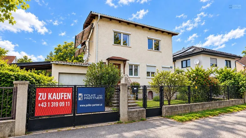Einfamilienhaus mit gepflegtem Vorgarten und Zaun, bereit zum Verkauf.