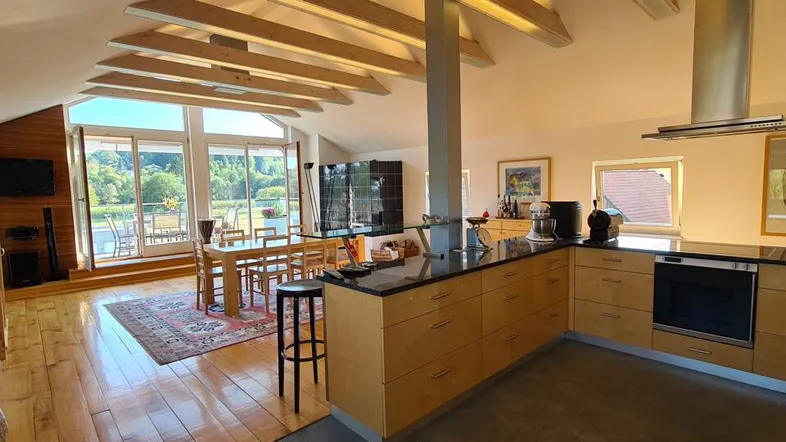 Moderne Küche mit Holzelementen, Essbereich und Zugang zu einer großen Terrasse.