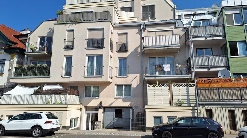 Modernes Mehrfamilienhaus mit mehreren Balkonen und Terrassen in städtischer Umgebung.