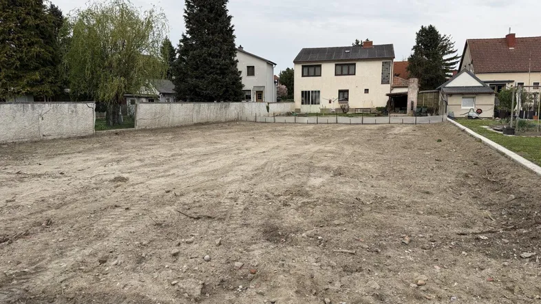 Freies Baugrundstück in ländlicher Umgebung mit Blick auf umliegende Häuser und Bäume.