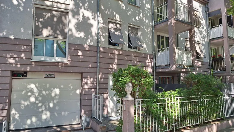 Fassade eines Mehrfamilienhauses mit integrierter Garage, Balkonen und Fensterläden.