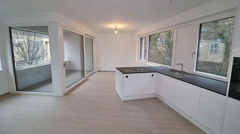 Heller offener Wohn- und Essbereich mit integrierter Küche, Balkonzugang und modernem Design.