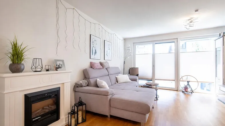 Helles Wohnzimmer mit gemütlichem Ecksofa, Kamin und Zugang zur Terrasse.