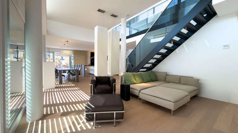 Helles, offenes Wohn- und Esszimmer mit moderner Treppe, Holzboden und viel Tageslicht.