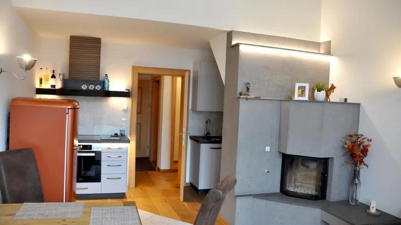 Gemütlicher Wohn-Essbereich mit integrierter Küchenzeile, Holzboden und modernem Kamin.