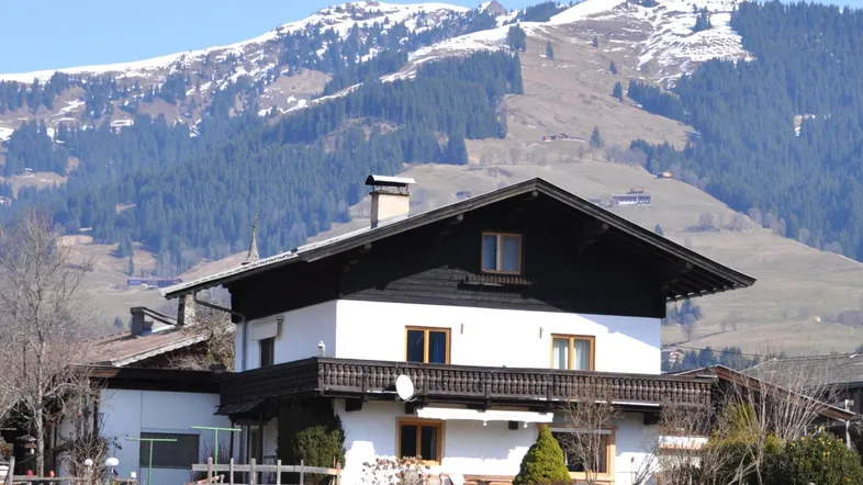Traditionelles Haus im alpinen Stil mit Holzbalkon und beeindruckendem Bergblick.