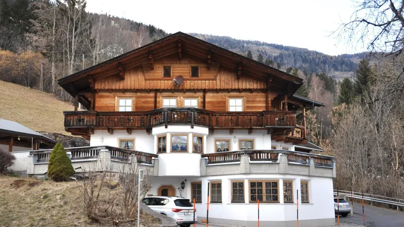 Großes traditionelles Holzhaus im Chalet-Stil mit mehreren Balkonen und Bergblick.