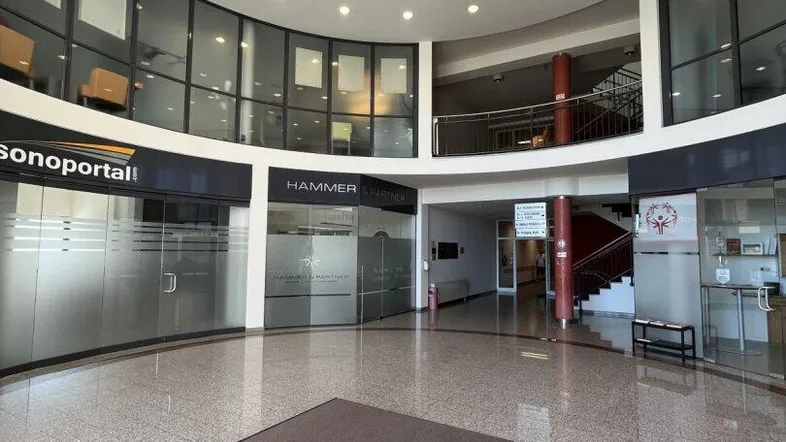 Geräumige und helle Lobby eines Geschäftsgebäudes mit glänzenden Fliesenböden und Glasfassaden.