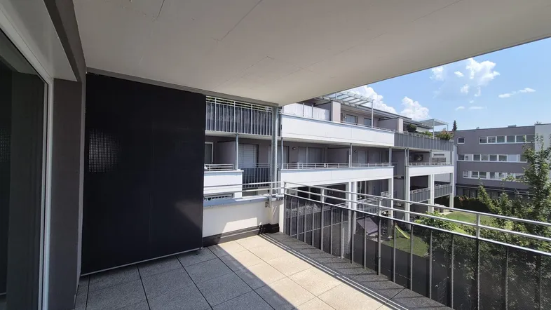 Geräumiger Balkon mit Fliesenboden und Blick auf die umliegenden Gebäude und Grünflächen.