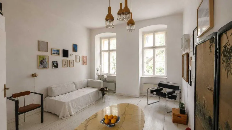 Helles Wohnzimmer mit weiß gestrichenen Dielenböden, hohen Fenstern und moderner Einrichtung.