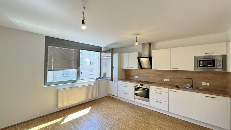Helle, moderne Küche mit weißen Schränken, Holzarbeitsplatte und Blick auf die Stadt.