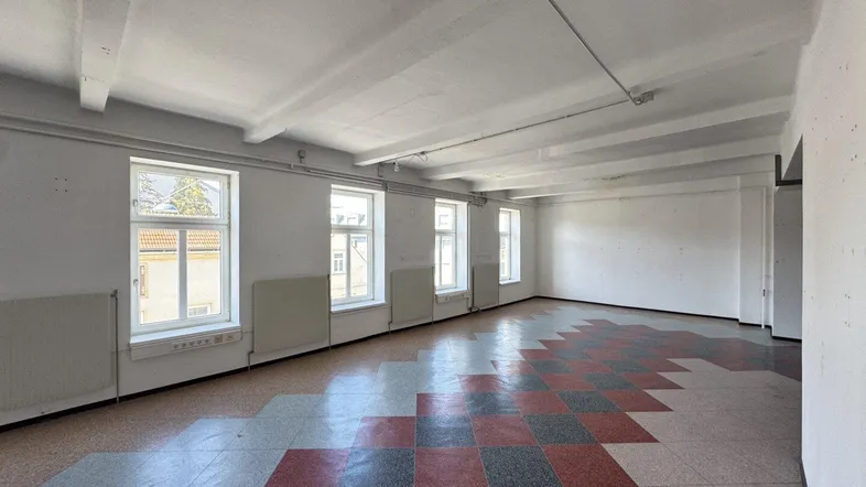 Großer, leerer Raum mit hohen Decken und einem markanten Fliesenbodenmuster.