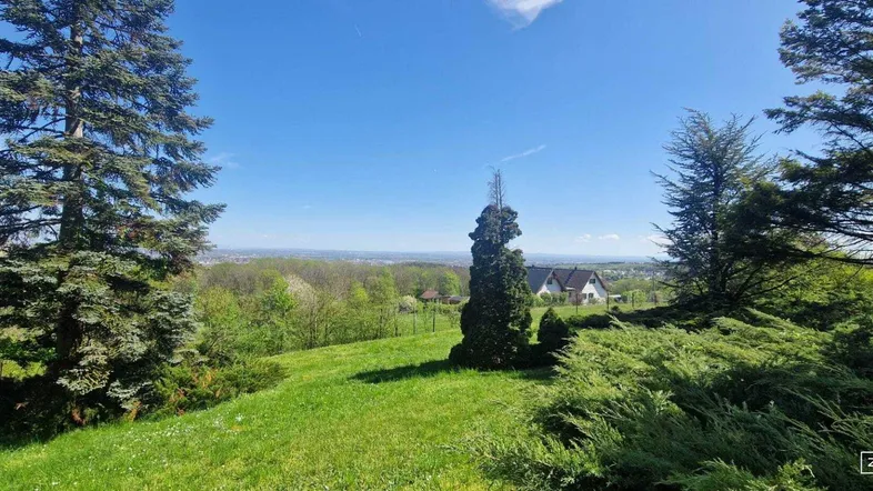 Weitläufiger Gartenbereich mit üppiger Vegetation und Panoramablick in die Ferne unter blauem Himmel.