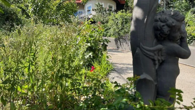Villa mit geschwungenem Dach und üppiger Vegetation, umgeben von einem gepflegten Garten.