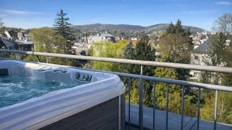 Whirlpool auf dem Balkon mit weitem Blick über die Stadt und grüne Hügel.