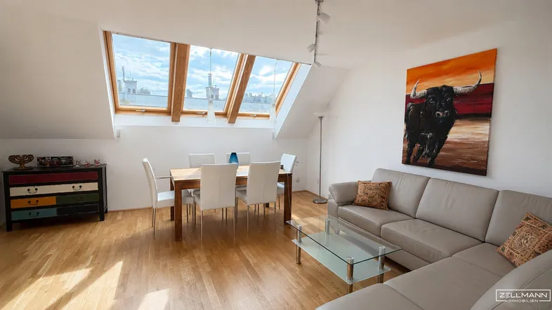 Helles Wohn- und Esszimmer im Dachgeschoss mit Holzboden und großen Dachfenstern, ideal für gemütliche Abende.