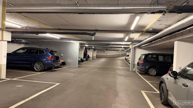 Geräumige Tiefgarage mit mehreren Stellplätzen und guter Beleuchtung durch Leuchtstoffröhren.
