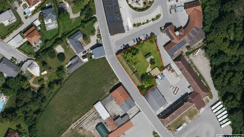 Luftaufnahme eines Grundstücks mit roter Umrandung, umgeben von Wohngebäuden und Straßen.