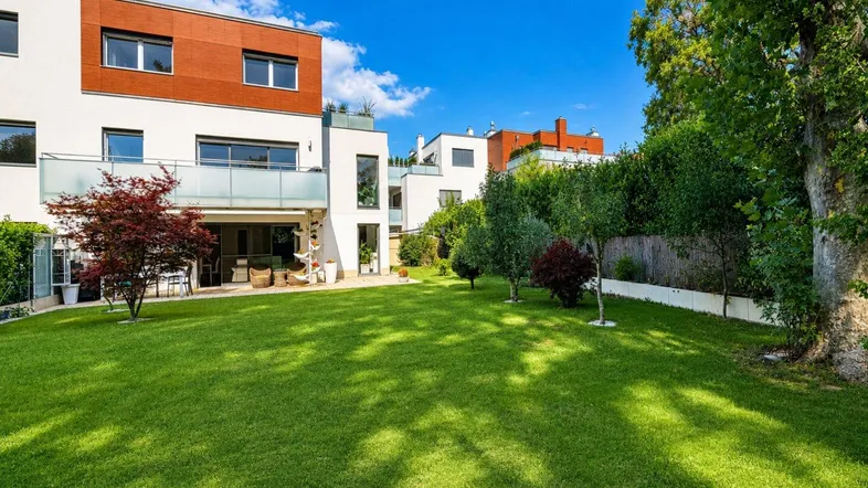 Moderne Wohnanlage mit gepflegtem Rasen und Terrassen in einer grünen Umgebung.