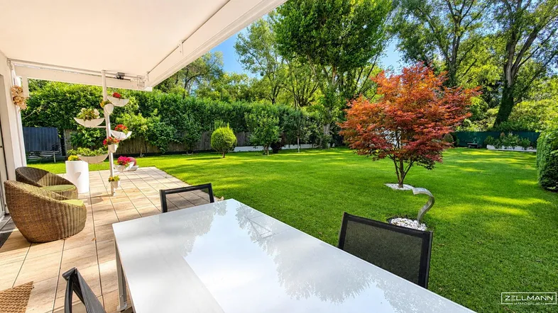 Gemütliche Terrasse mit Esstisch und Stühlen, umgeben von einem grünen Garten.