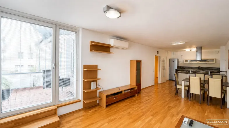 Heller offener Wohn- und Essbereich mit Holzboden, großen Fenstern und Zugang zu einer Terrasse.