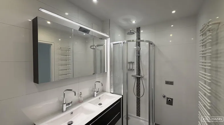 Modernes Badezimmer mit Doppelwaschbecken, Duschkabine und integriertem Spiegelschrank.