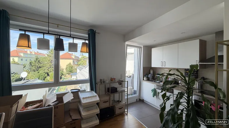 Helles Wohnzimmer mit offener Küche, Parkettboden und weitem Blick ins Grüne.