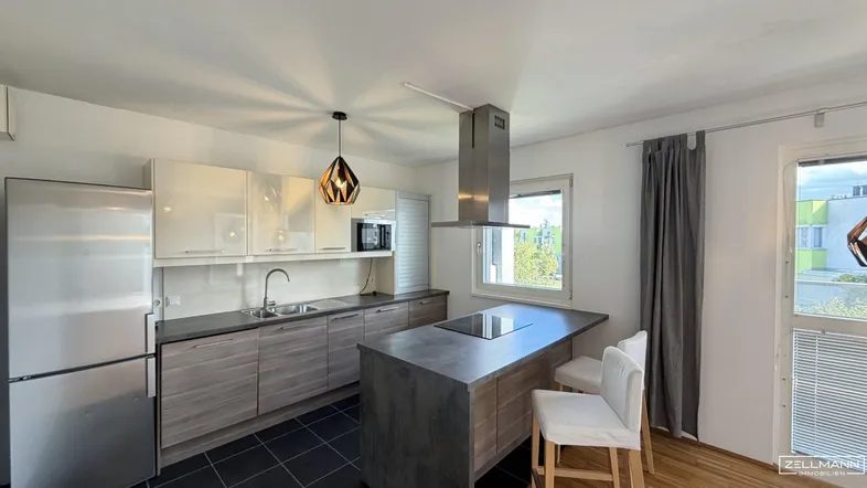 Moderne Küche mit Kücheninsel, Einbaugeräten und Fenster, ausgestattet mit hellen und holzfarbenen Schränken.
