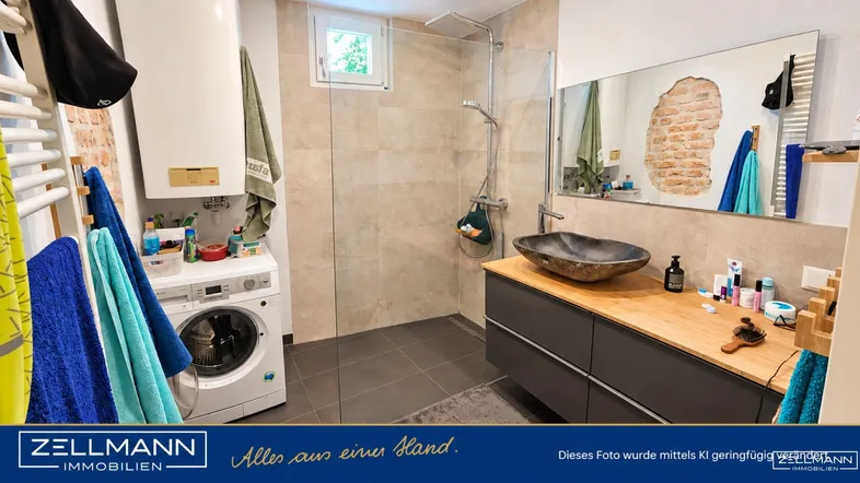 Modernes Badezimmer mit ebenerdiger Dusche, Waschmaschine und freiliegender Ziegelwand.