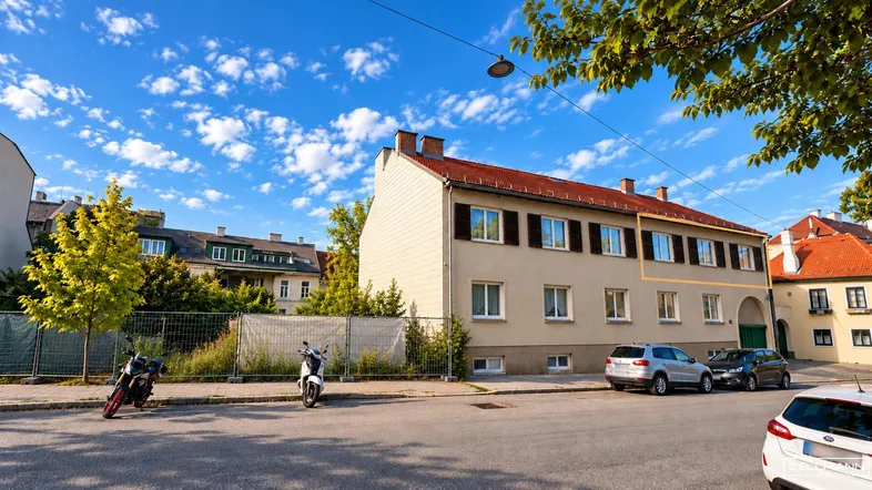 Ansicht eines Mehrfamilienhauses von der Straße mit gepflegter Fassade und grüner Umgebung.
