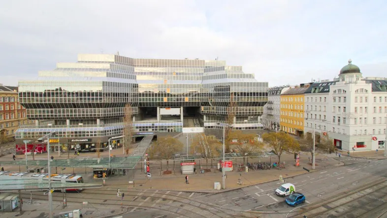 Weitläufige Ansicht eines modernen Gebäudekomplexes mit Glasfassade und belebter Straßenkreuzung.