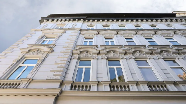 Detailansicht der historischen Fassade eines Altbaus mit reich verzierten Fenstern und Balkongeländern.