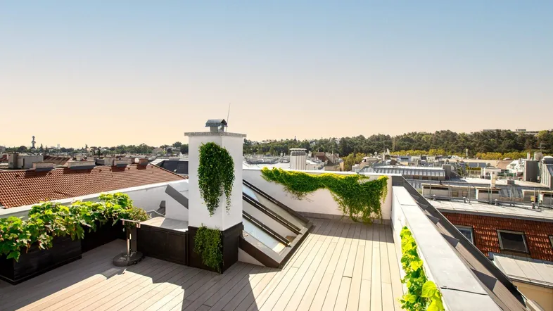 Geräumige Dachterrasse mit Holzbelag, Pflanzen und weitem Blick über die Stadt.