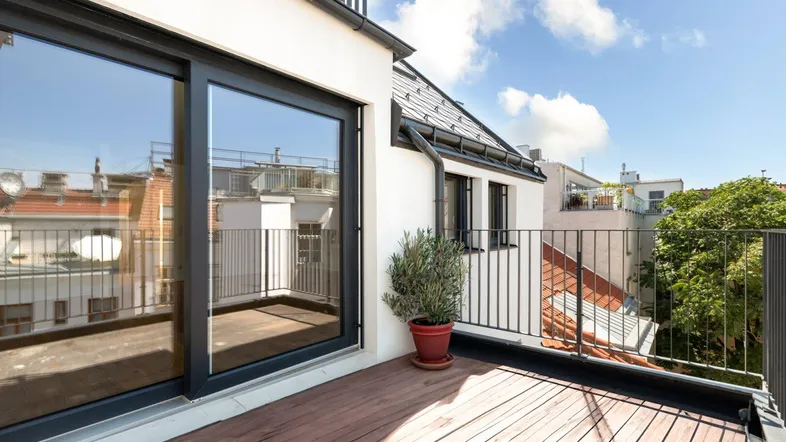 Heller Balkon mit Holzboden und Blick auf die umliegenden Dächer, ideal für entspannte Stunden im Freien.
