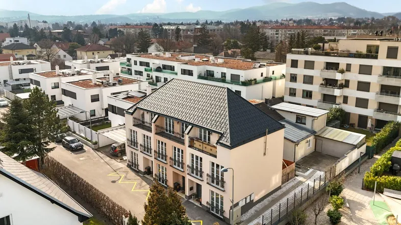 Luftaufnahme einer modernen Wohnanlage mit mehreren Gebäuden und umliegender grüner Landschaft.