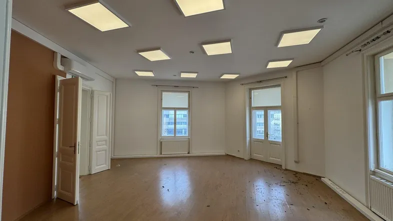 Geräumiger, leerer Raum mit Holzparkettboden und modernen Deckenleuchten, bereit zur Gestaltung.