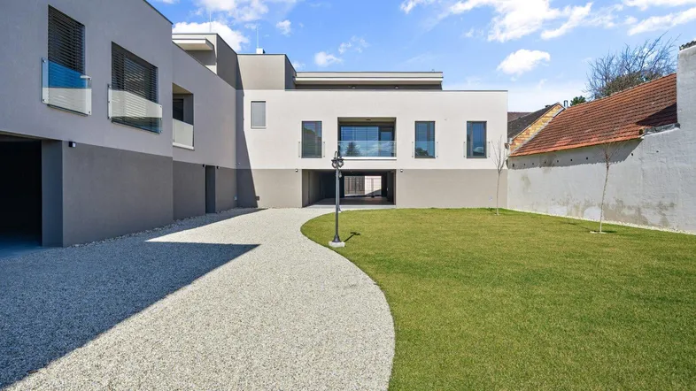 Moderne Wohnanlage mit Kiesweg, Rasenflächen und zeitgenössischer Architektur.